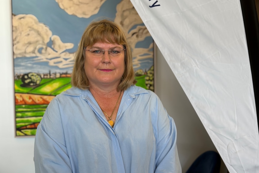 A woman in a blue linen shirt standing