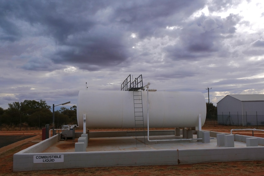 Large white fuel storage tank sits outside.