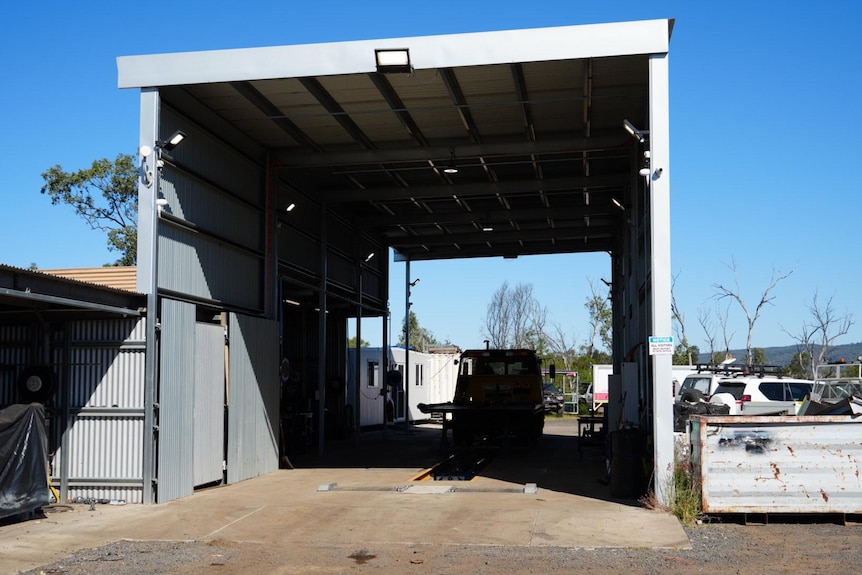 A tall shed in a car repair yard.