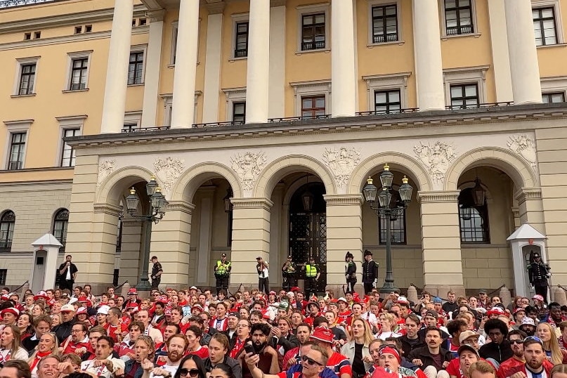 dozens of norwegian fans 'row' in front of a palace building