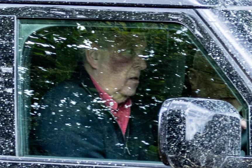 Andrew seen through the window of a car, with a red, purplish mark on his cheek.