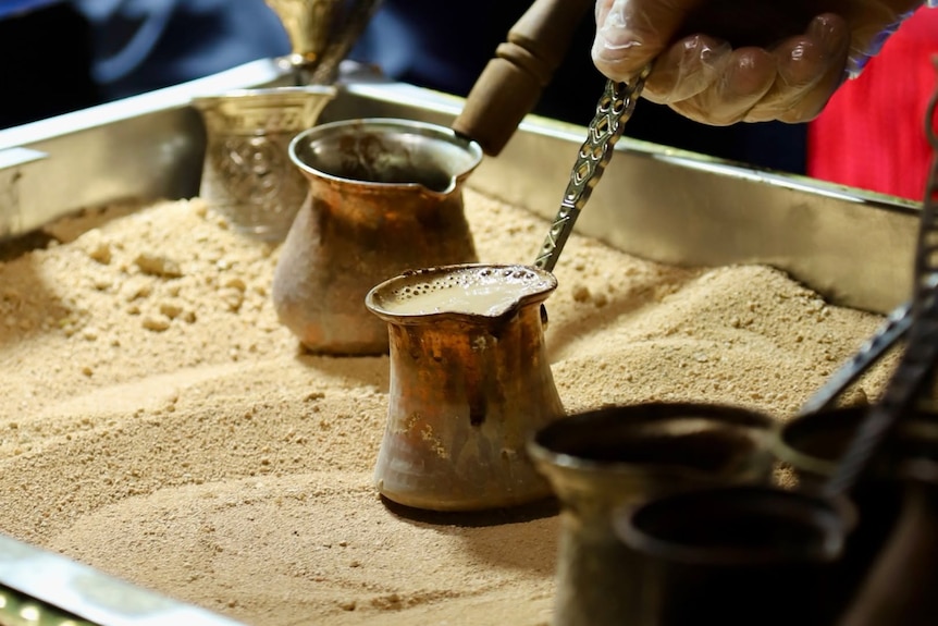 a hand holding a small arabic tea pot