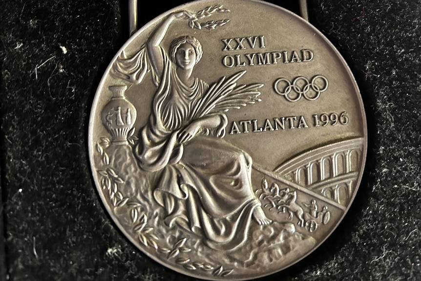 A silver Olympic medal for the 1996 Olympics held in Atlanta inside a black velvet case.