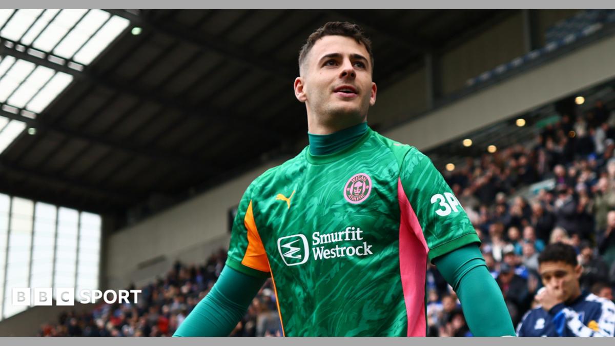 Wigan Athletic goalkeeper Sam Tickle walking out before an EFL football match, wearing a green goalkeeping top.