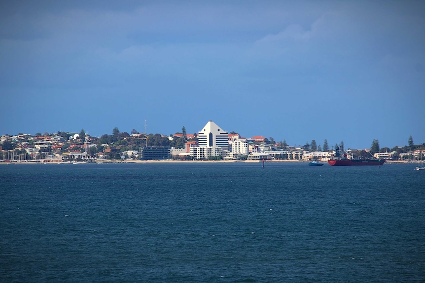 A built-up town skyline as seen from across a stretch off ocean.