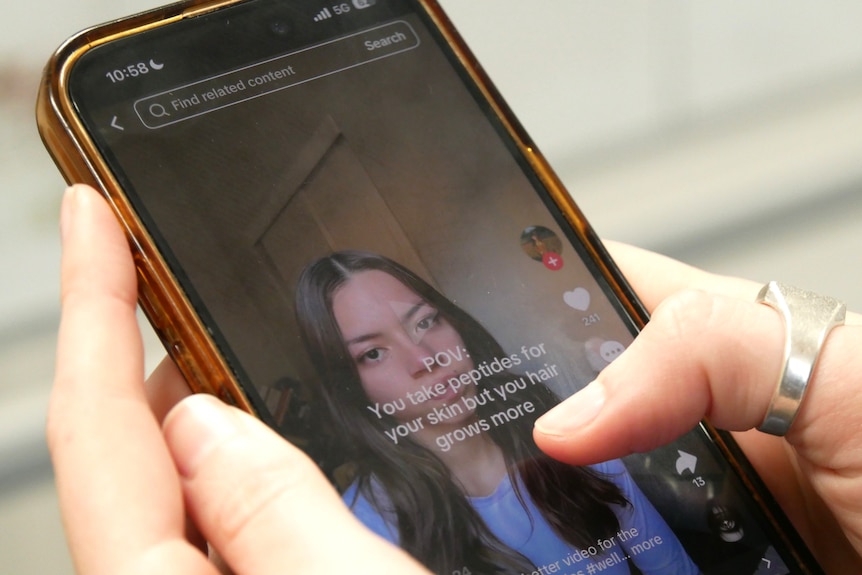 Fingers hovering over a phone showing a video about peptides.