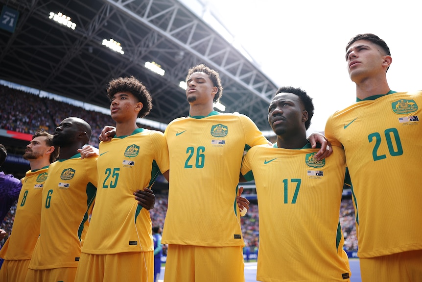 Socceroos players sing the national anthem
