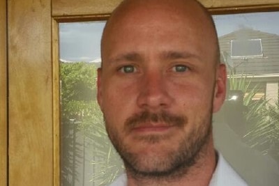 A bald man wearing a white shirt.