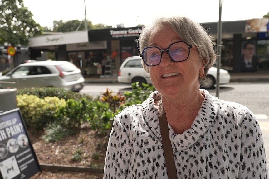 Annette Wilkins speaking on a street with shops in the background.