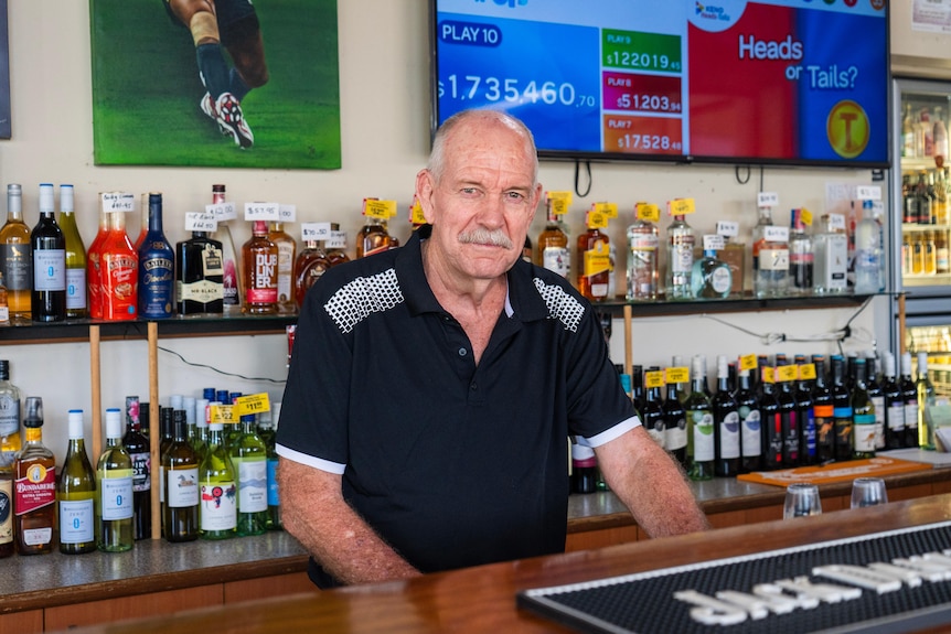 a man stands behind a bar.
