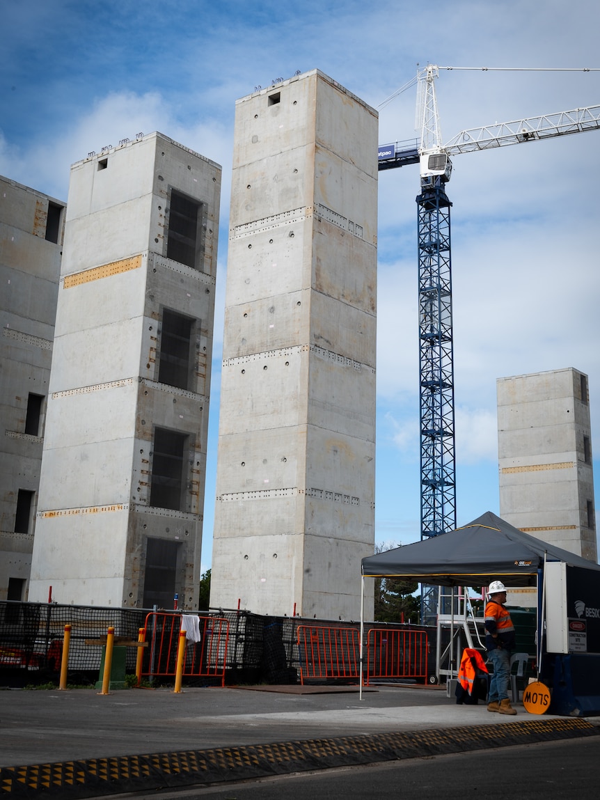 Centre pillars of building under construction at Maroochydore CBD entrance onto job site traffic control worker in forground