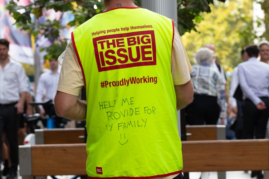 The back of a man wearing a hi-vis vest for The Big Issue with message 'help me provide for my family'