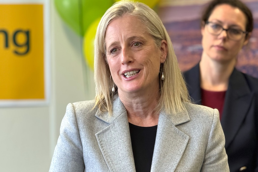 Minister for Finance Katy Gallagher speaking, wearing a grey blazer, smiling warmly at Woden Bulk billing clinic, Canberra.