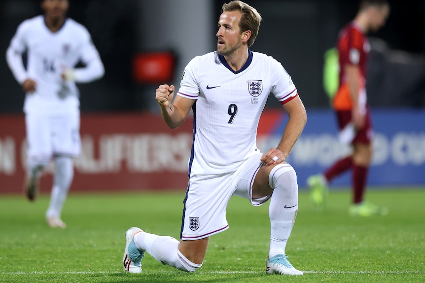 Harry Kane kneels as he celebrates scoring a goal for England against Latvia.