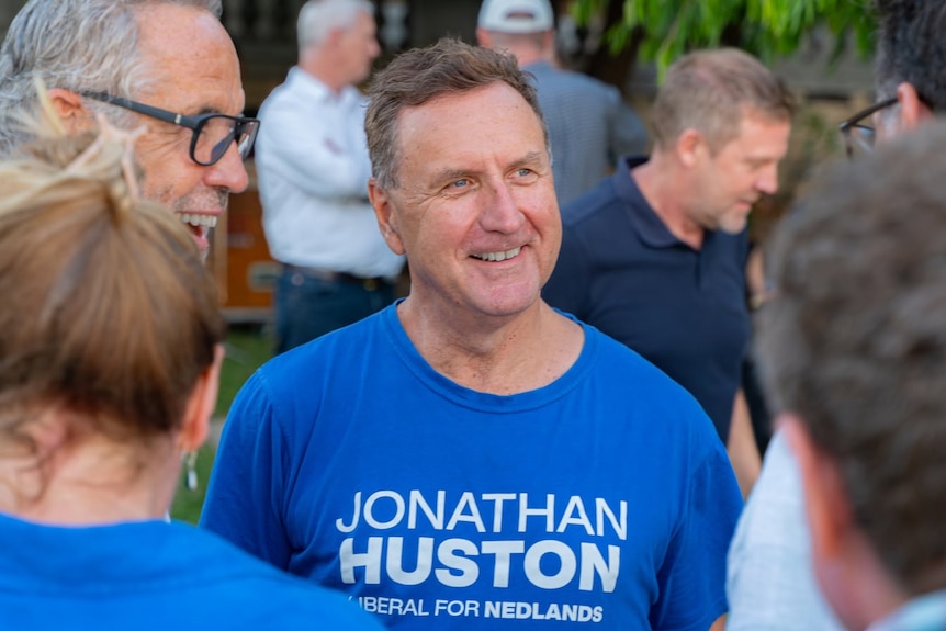 A man wearing a Liberal shirt speaking with other men