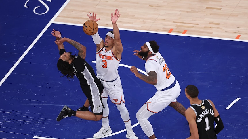A San Antonio NBA player's shot is blocked by a New York Knicks player in a finals game.