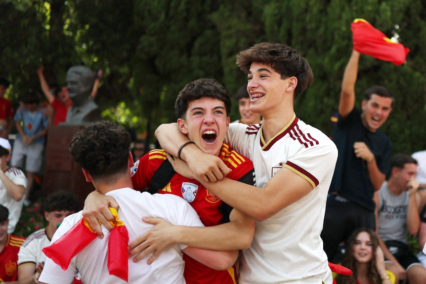three boys in spanish jerseys cheer and hug each other 