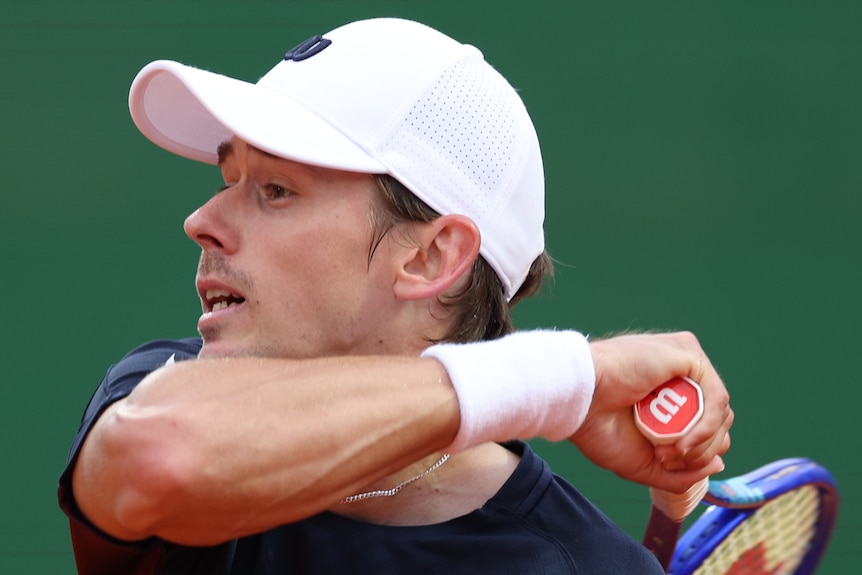 Alex de Minaur completes his forehand swing over his shoulder during a tennis match.