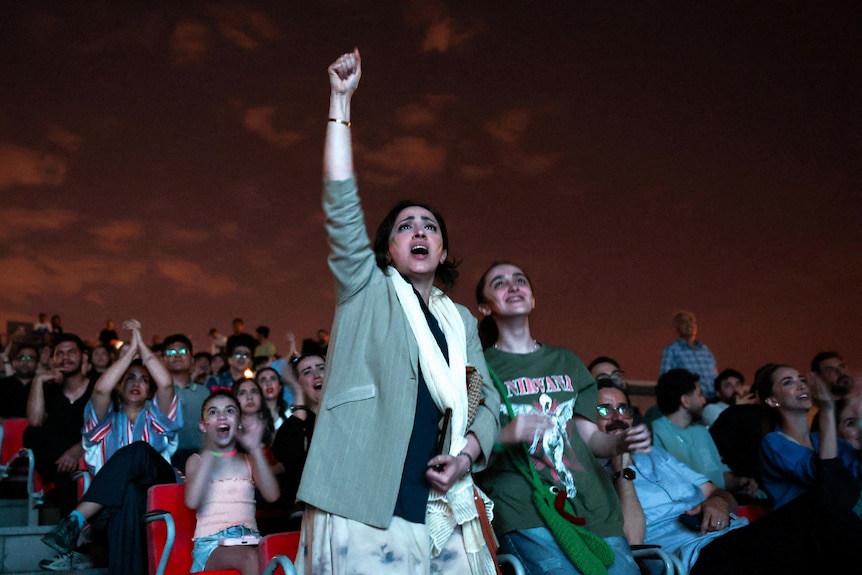a woman stands defiant fist in the air celebrating