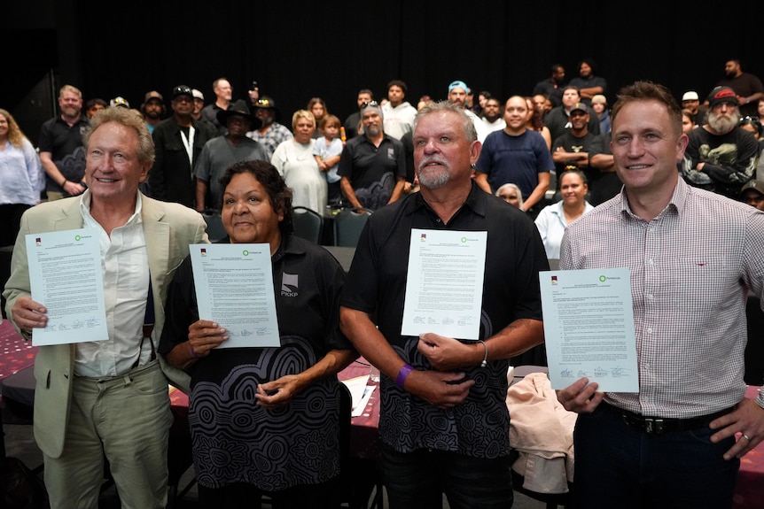 Andrew Forrest, PKKP elder Sandra Hayes, PKKP elder Terry Drage, and Fortescue CEO Dino Otranto hold up signed documents.
