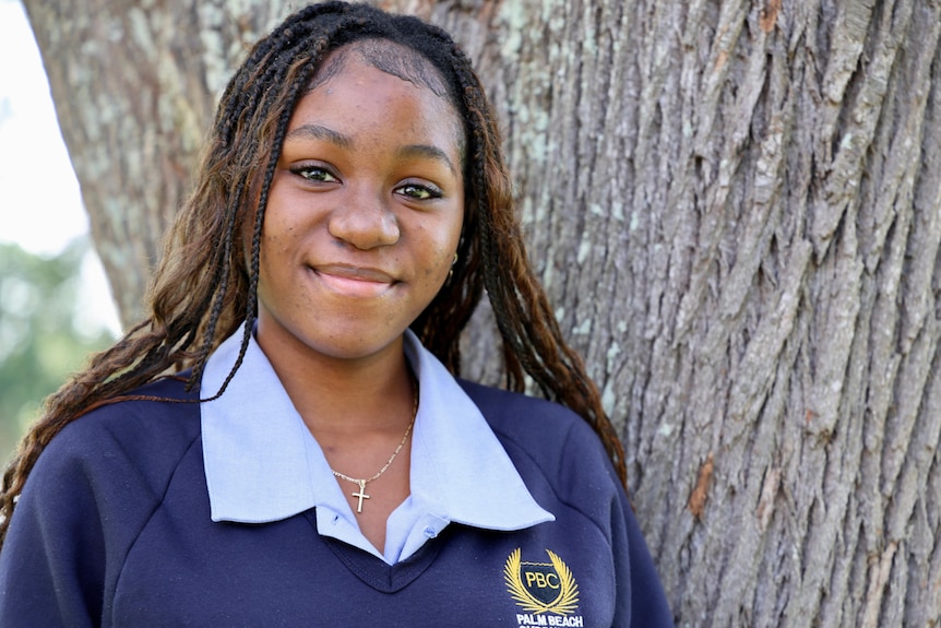 A schoolgirl smiling in front of a tree