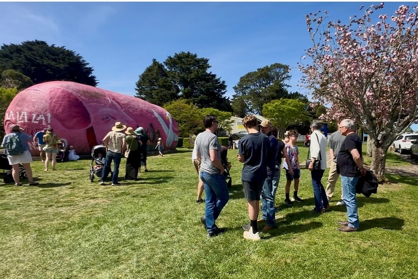 people standing around pink painted structure in green park