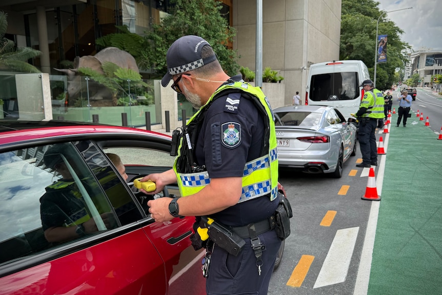 Queensland police holding breath testing units while pulling over drivers