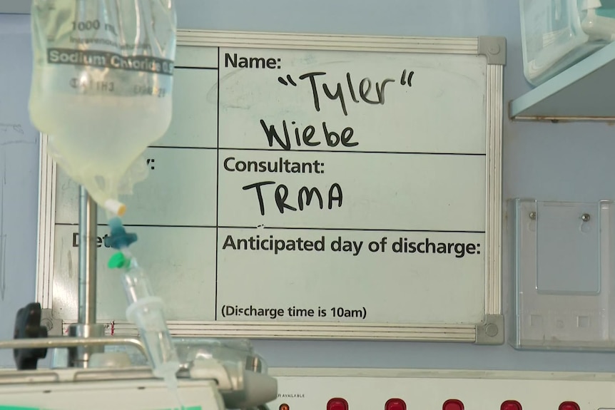 A whiteboard reading 'Tyler Weibe' and 'TRMA', with an IV drip bag in front.