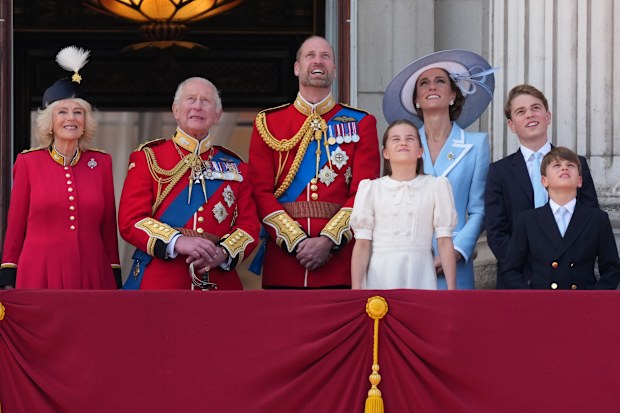 Britain's King Charles III, second left and Queen Camilla, left look up as they watch a fly past by military planes from the balcony of Buckingham Palace, with other members of the royal family, Prince William, Kate Princess of Wales, Princess Charlotte, Prince George and Prince Louis