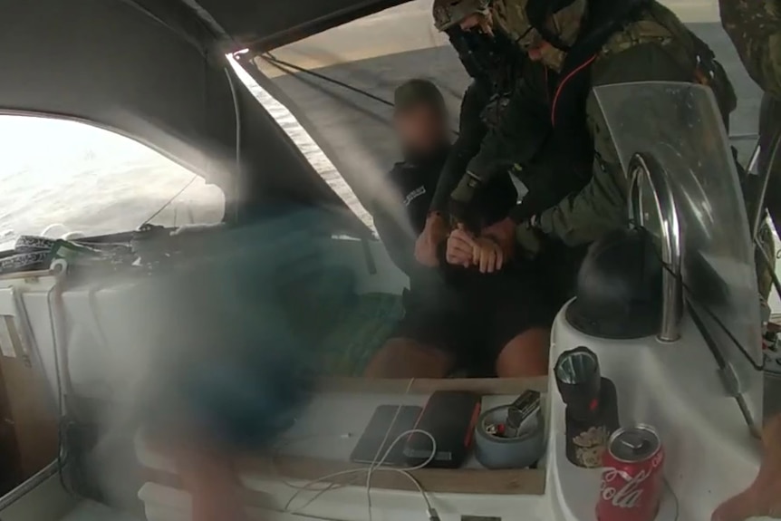 a blurry picture from the inside of a yacht of a man being detained