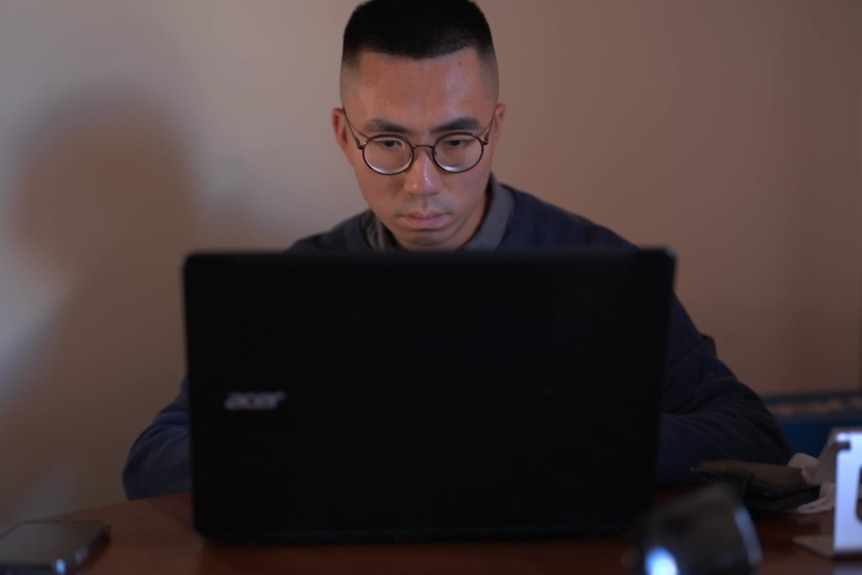 A man at a table works on his laptop