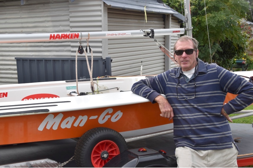 a man wearing a striped long-sleeve polo next to a boat.