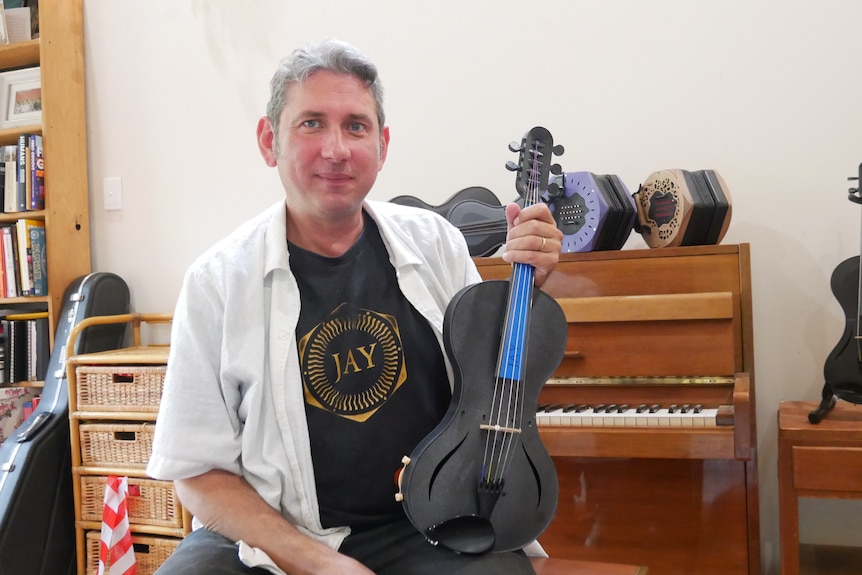 A medium shot of a man holding a violin