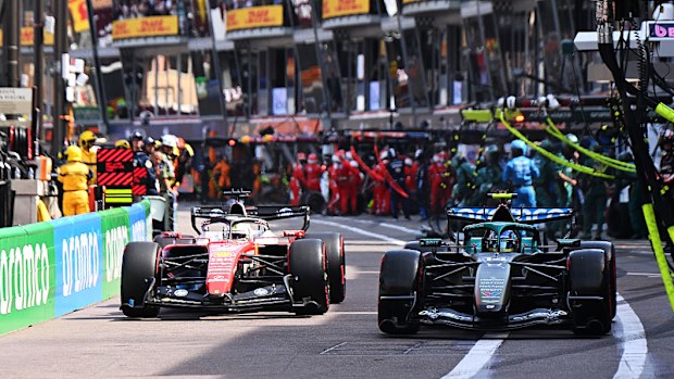 Two Formula 1 cars in a pit lane.