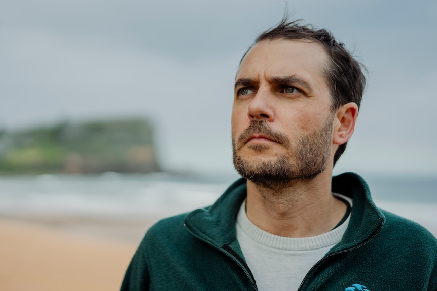 Lawrence Chlebeck from Marine for Humane World for Animals stands at a beach looking to the side