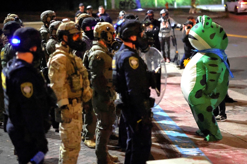 An inflatfrog stands next to armed troops.