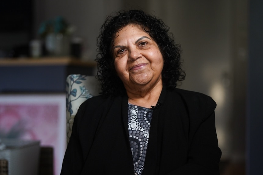 A woman with a warm expression sitting on a chair.