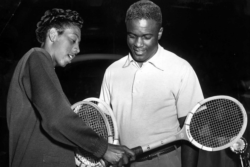 Althea Gibson shows off her tennis grip while talking to baseball icon Jackie Robinson.