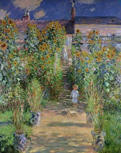A vibrant garden path overflowing with colorful flowers leads toward a sunlit house, painted with lively brushstrokes in The Artist's Garden at Vétheuil by Claude Monet.