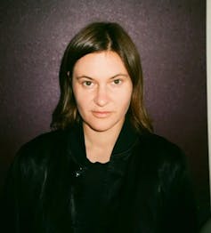 a young woman with dark hair, dressed in black