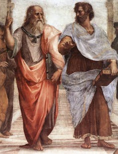 A faded fresco shows two bearded men in robes gesturing as they speak with each other.