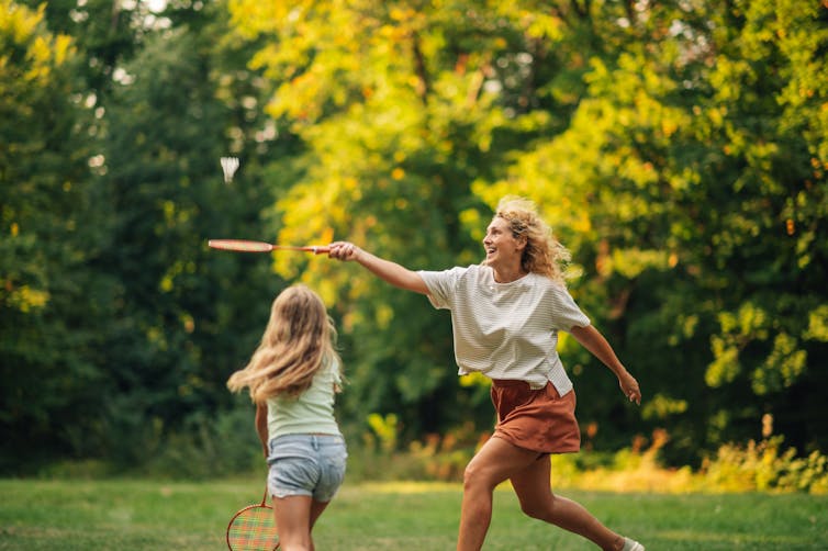 Woman and girl play badminton in a park