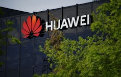 The Huawei logo on a building framed by trees