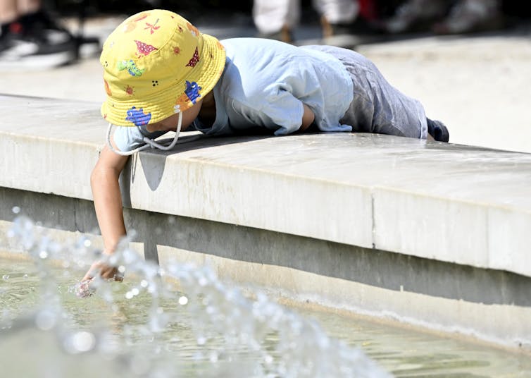 A child cools down at a fountain during a heatwave in Milan, Italy