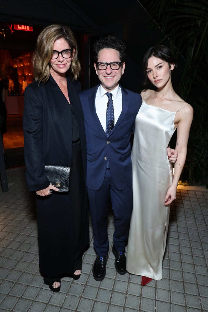 Katie McGrath, J.J. Abrams, and Gracie Abrams pose together at an event, with Gracie wearing a white slip dress.