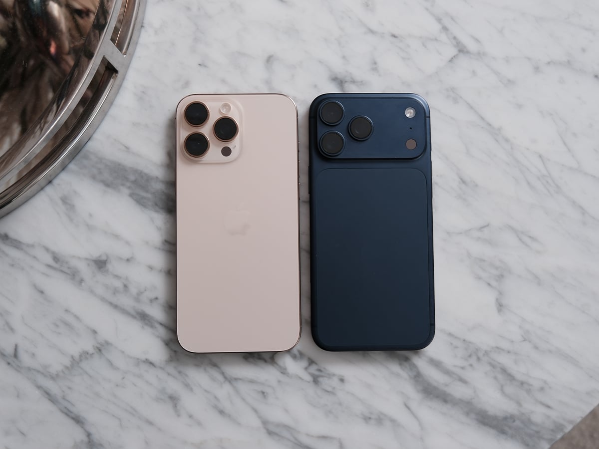 iPhone 17 Pro Max in gold next to iPhone 16 Pro Max in blue on a marble surface.