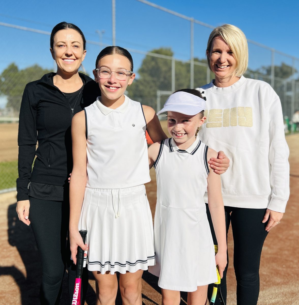 two mothers with daughters on tennis court