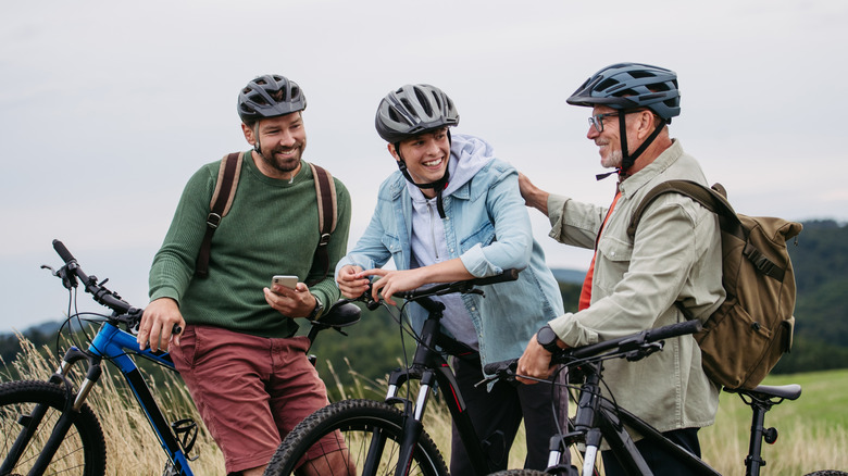 Three cyclists relax on their bikes in a rural area on an overcast day