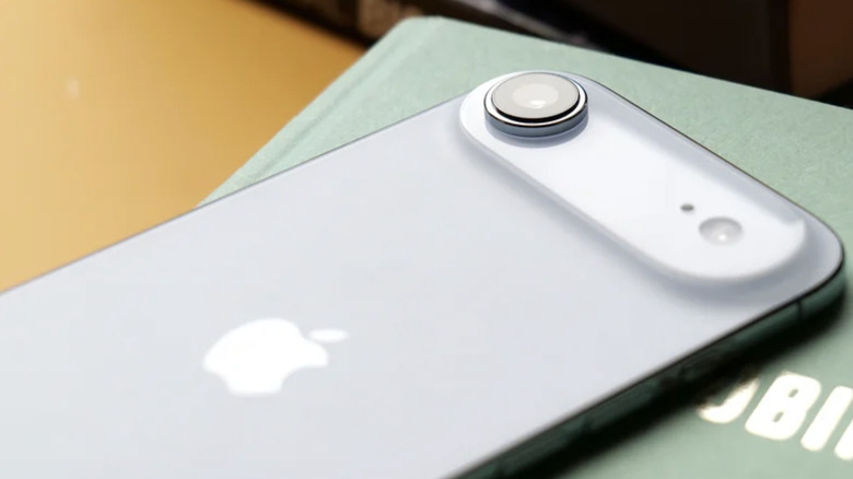 Photo showing the back camera of an iPhone Air. The white smartphone rests on top of a green hardcover book.