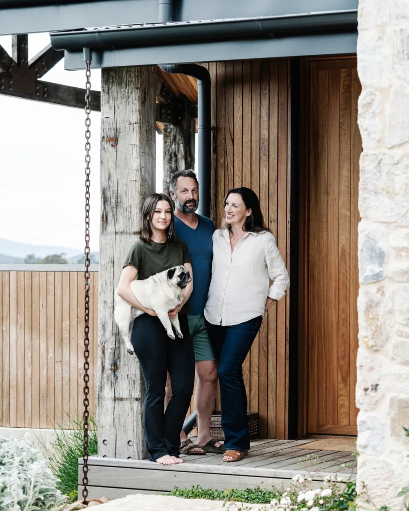 The homeowners standing out the front of their country home with their daughter holding their pet pug.